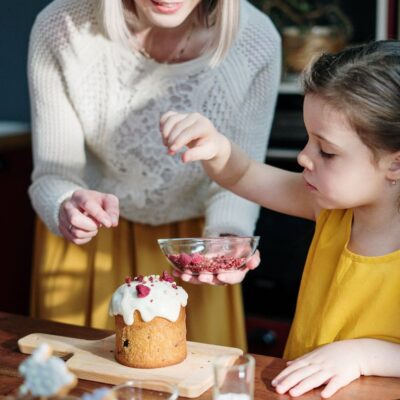 Niña con su madre en la cocina de su casa decorando un pastel