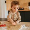 Niño pequeño apoyado en mesa haciendo formas a una masa de galletas