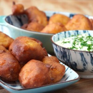 Bandeja con buñuelos de bacalao y, al lado, un recipiente con salsa de ajo