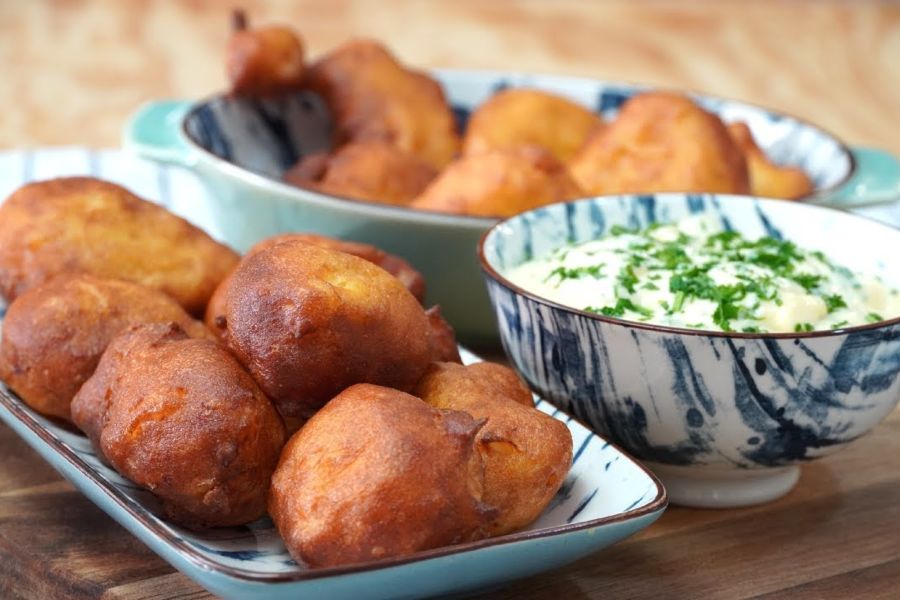 Bandeja con buñuelos de bacalao y, al lado, un recipiente con salsa de ajo