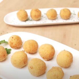 Dos bandejas blancas con croquetas redondas de gambas