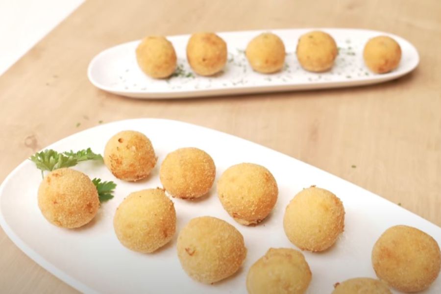 Dos bandejas blancas con croquetas redondas de gambas