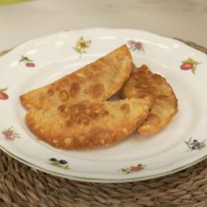Plato con tres empanadillas de carne sobre mantel en mesa