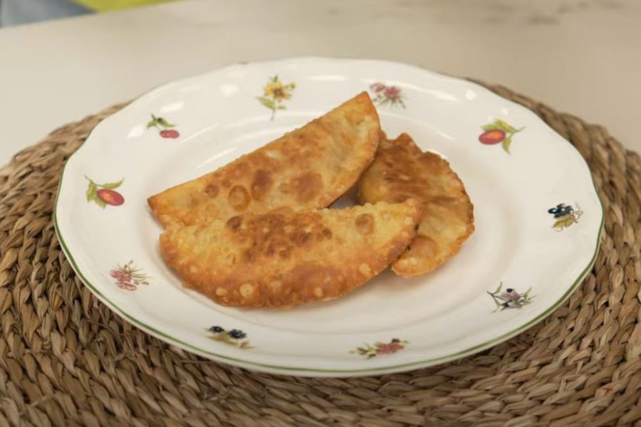 Plato con tres empanadillas de carne sobre mantel en mesa