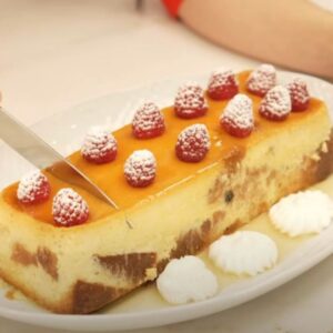 Detalle de manos de mujer con un cuchillo cortando un pudin casero sobre bandeja blanca