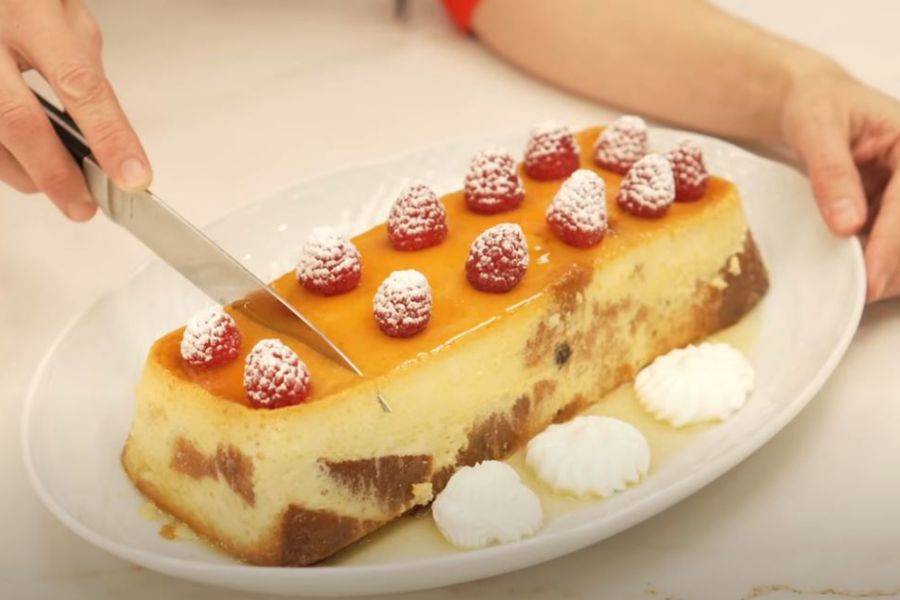 Detalle de manos de mujer con un cuchillo cortando un pudin casero sobre bandeja blanca
